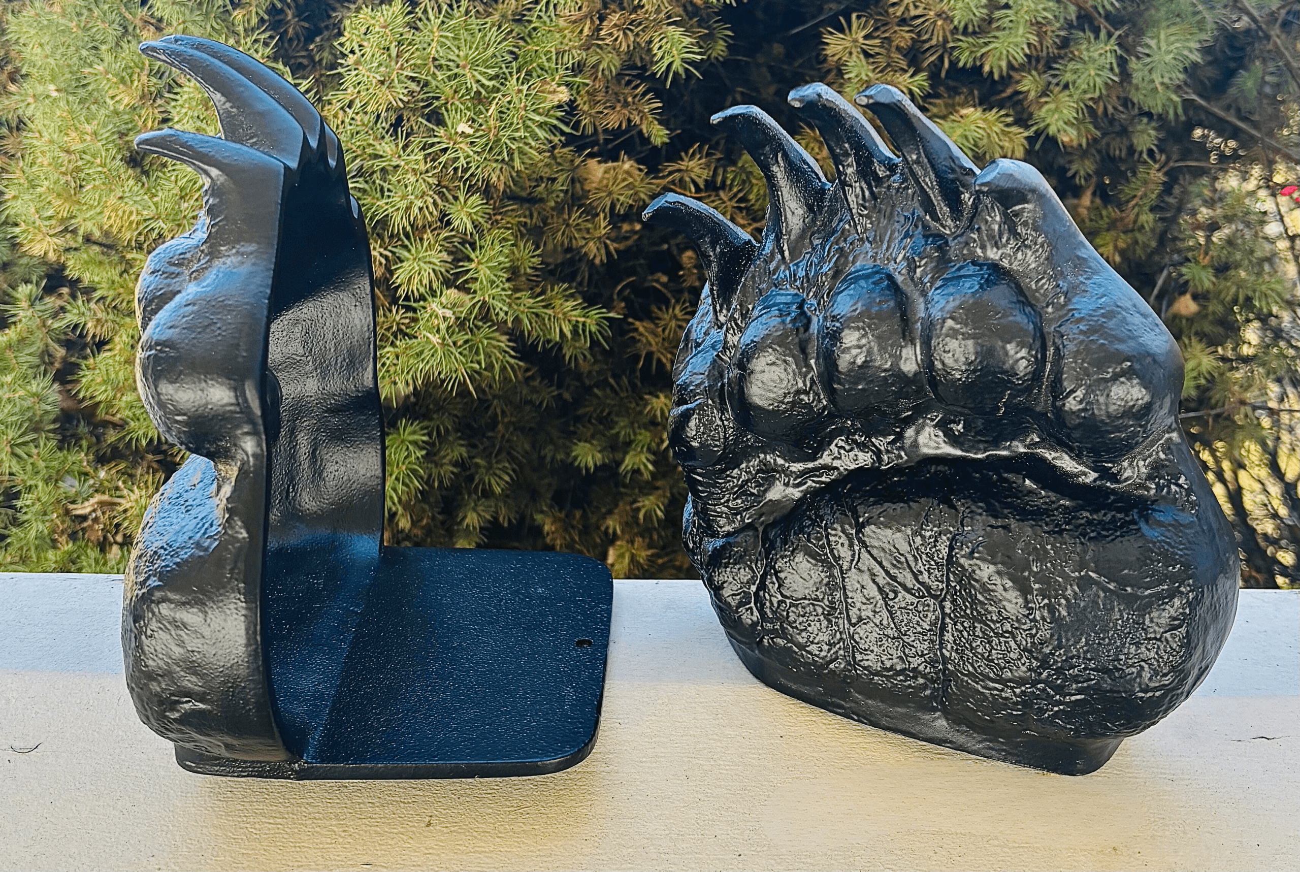 Black aluminum book ends shaped like grizzly bear tracks. One bookend is facing forward and one is facing sideways.